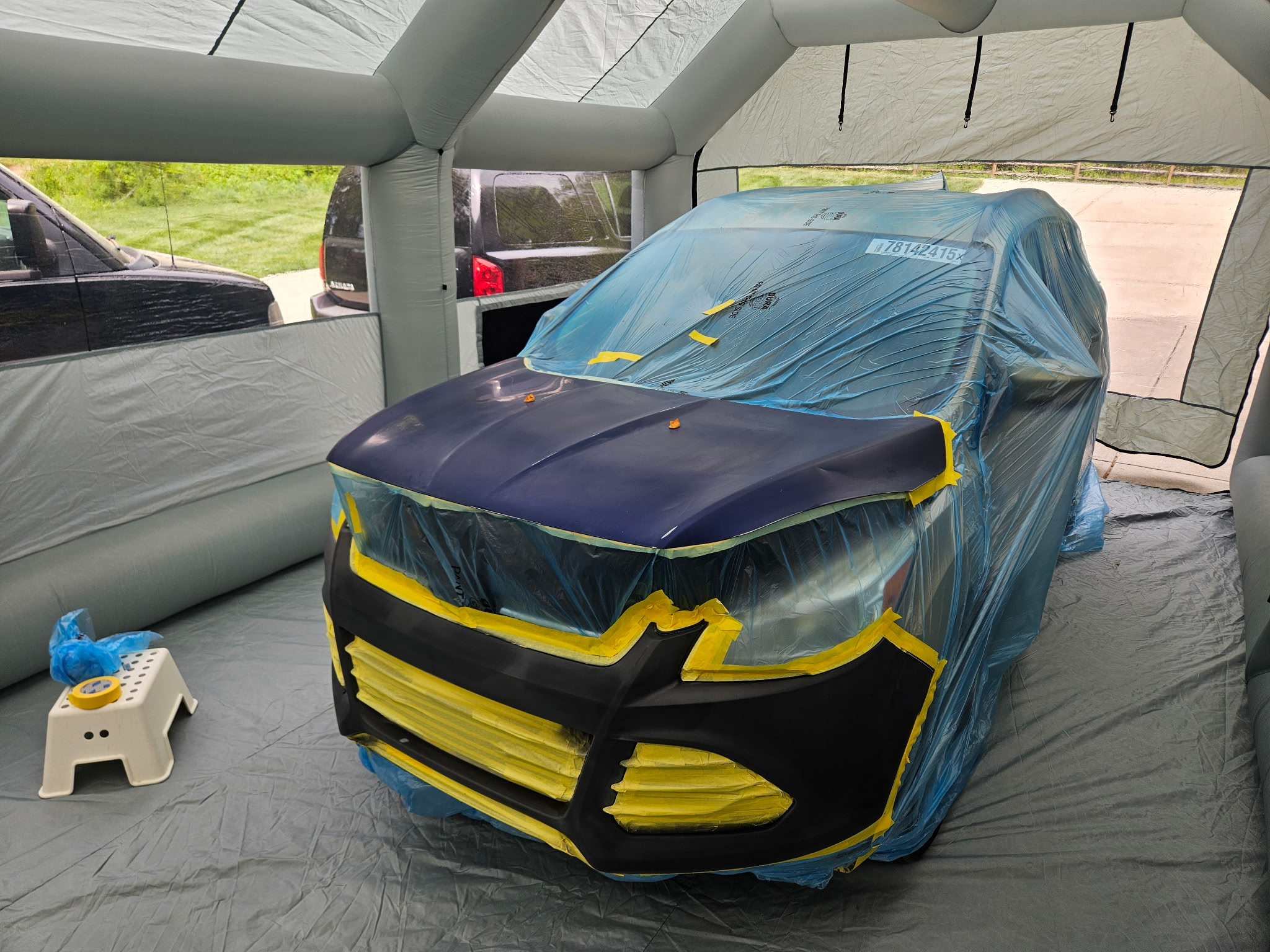 Quick Fix mobile spray booth set up at a customer location with a vehicle inside being prepped for repaint