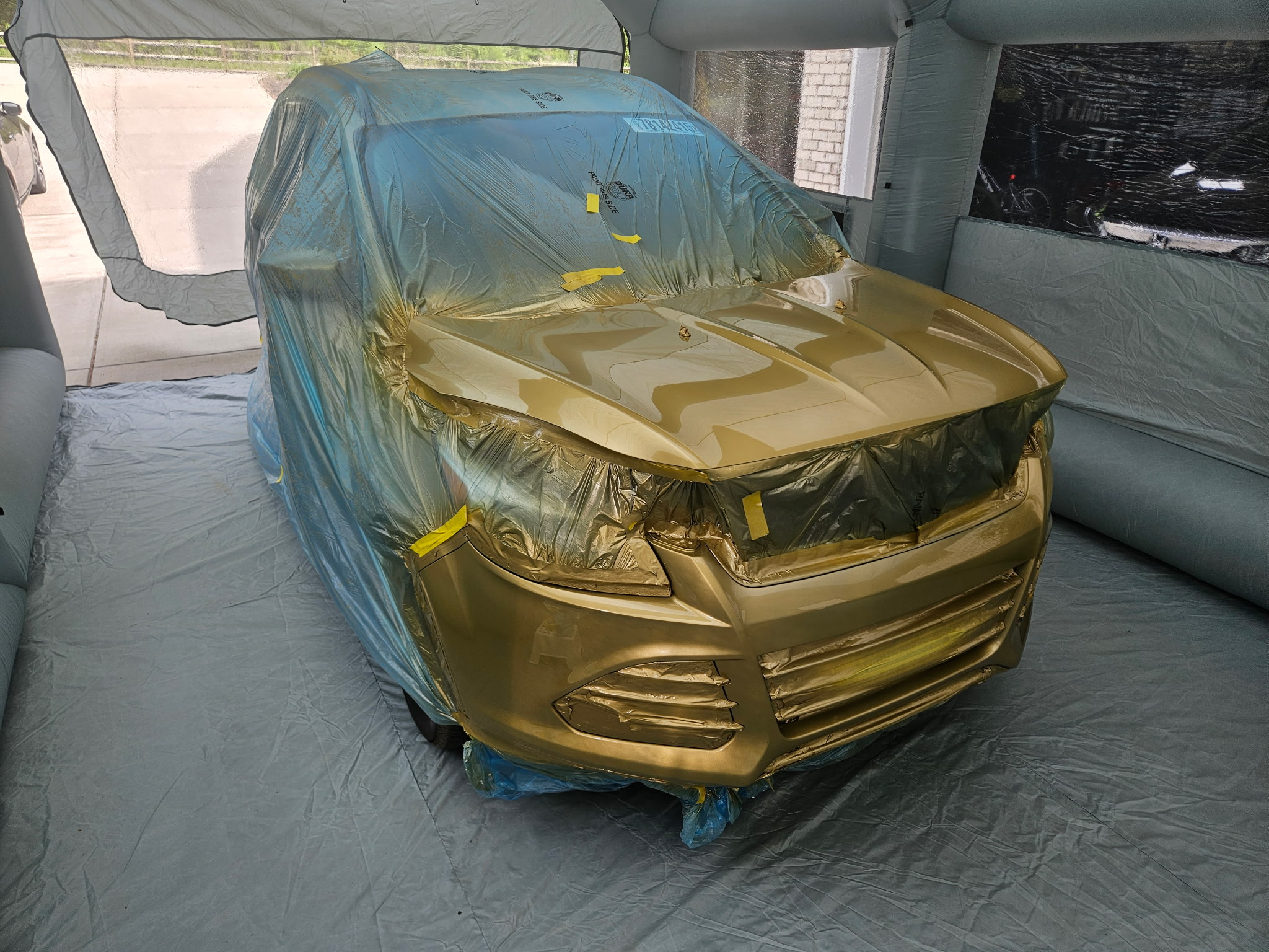Ford Escape under masking with new gold metallic paint applied in the spray booth