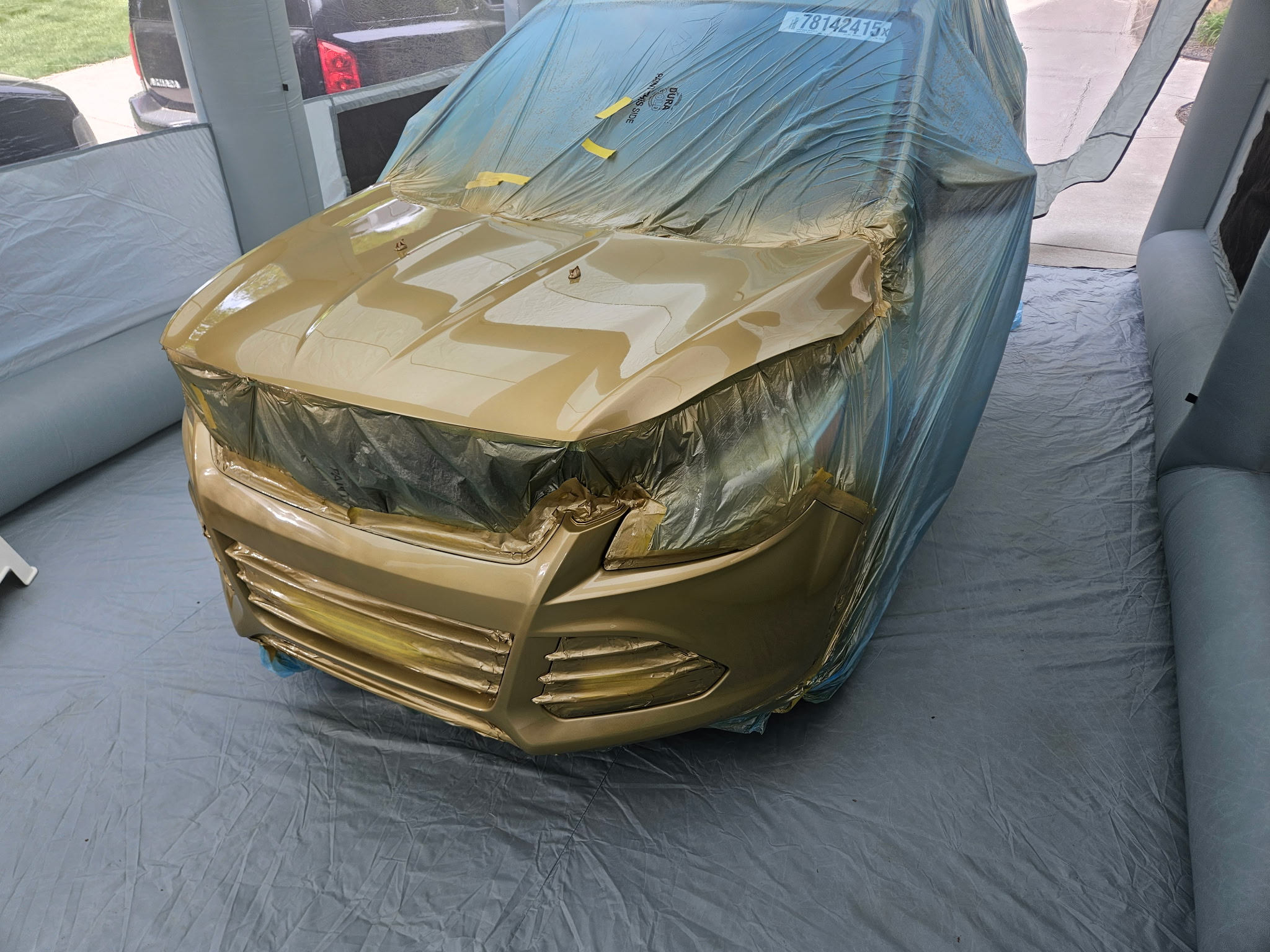 Close-up of gold-painted Ford Escape hood and bumper with masking still in place